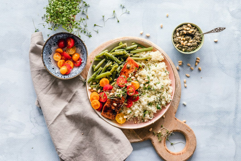 A balanced plate with salmon, grains, green beans and tomatoes